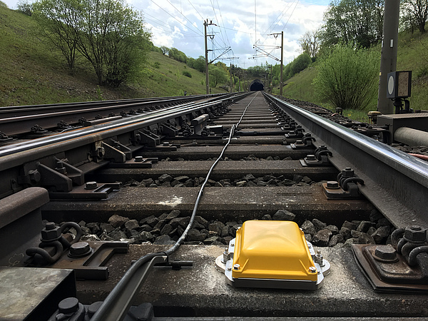 Der KONUX-Sensor wird direkt auf die Schwelle montiert und misst kontinuierlich wichtige Parameter wie Vibration und Beschleunigung, ohne den regulären Verkehrsfluss zu stören.