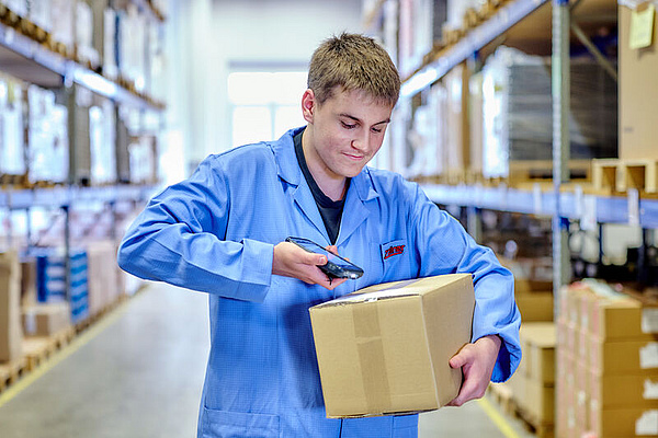 Ein Mitarbeiter scannt den QR-Code auf einem Paket.